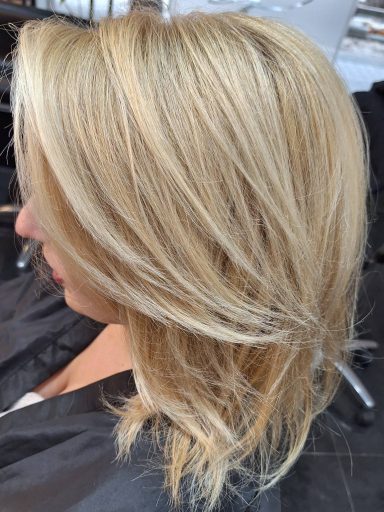 Media melena rubio dorado con mechas, tratada con coloración a base de óleos para un acabado brillante y saludable.